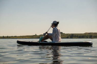 Sakin bir gölde yaz mevsiminde Serene Paddleboard yapan kadın