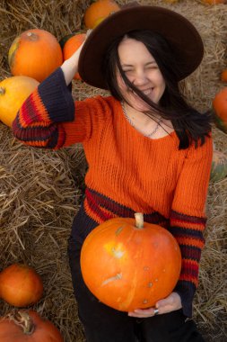 Saman balyalarında oturan balkabağını tutan kadının portresi