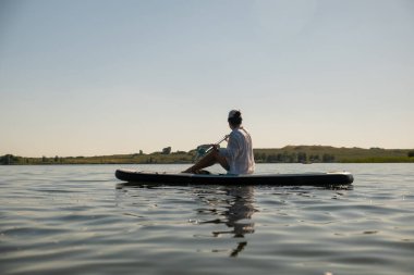 Sakin bir gölde yaz mevsiminde Serene Paddleboard yapan kadın