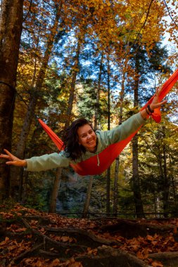 Sonbahar Ormanı 'nda bir hamakta gülümseyen bir kadın.