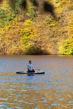 Man Supboarding in Autumn Foliage clipart