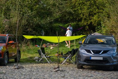 Camping Setup by the Riverbank with Cars summertime clipart