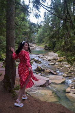 Serene Forest River 'ın yanındaki Kırmızı Elbiseli Gülümseyen Kadın