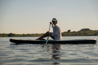 Sakin bir gölde yaz mevsiminde Serene Paddleboard yapan kadın