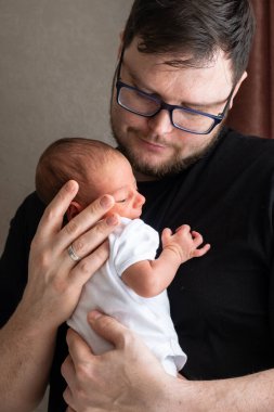 Yeni doğmuş bebeği şefkatli bir anda kucaklayan baba sevgisi