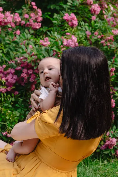 Çiçek açan bahçede Neşeli Anne ve Bebeğin Portresi