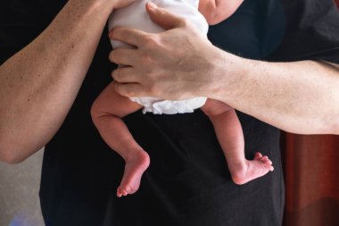 Yeni doğmuş bebeği şefkatli bir anda kucaklayan baba sevgisi