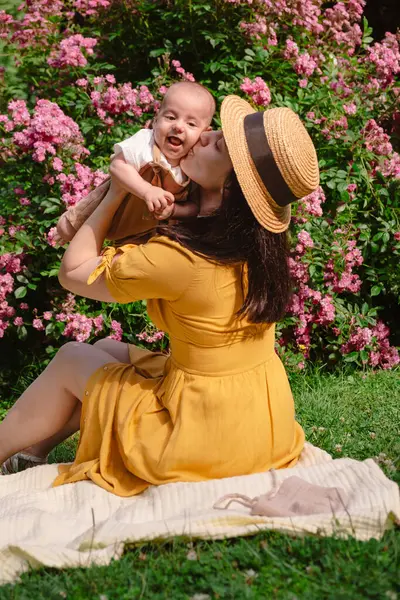 Çiçek açan bahçede Neşeli Anne ve Bebeğin Portresi