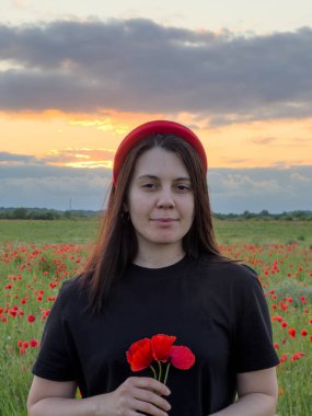 Haşhaş tarlasında kırmızı şapkalı genç kadın portresi