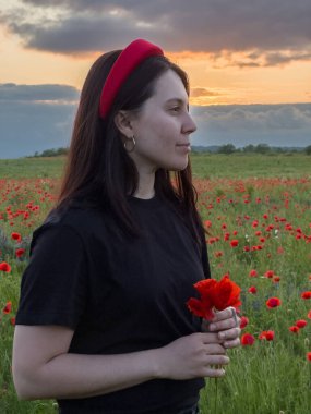 Haşhaş tarlasında kırmızı şapkalı genç kadın portresi