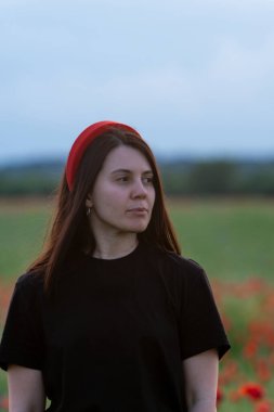 Haşhaş tarlasında kırmızı şapkalı genç kadın portresi