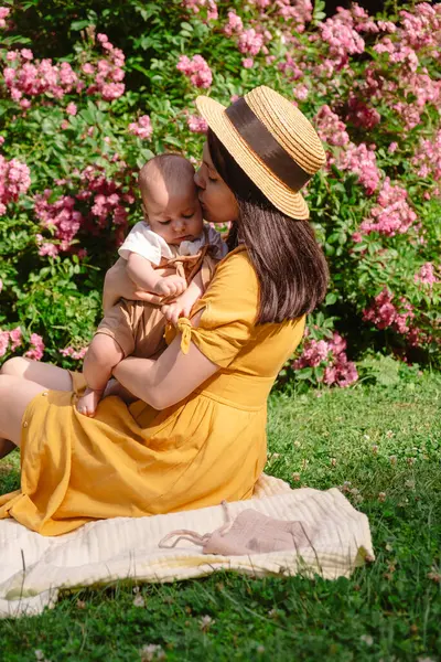 Çiçek açan bahçede Neşeli Anne ve Bebeğin Portresi