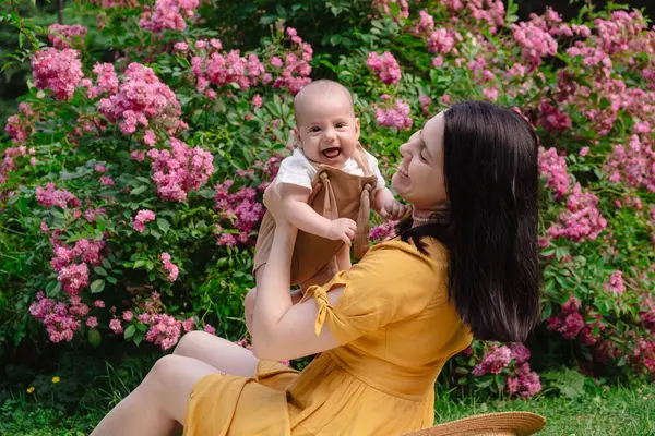 Çiçek açan bahçede Neşeli Anne ve Bebeğin Portresi