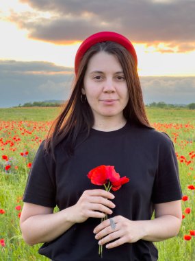 Haşhaş tarlasında kırmızı şapkalı genç kadın portresi