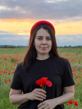 Haşhaş tarlasında kırmızı şapkalı genç kadın portresi