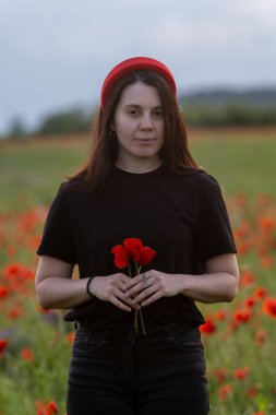 Haşhaş tarlasında kırmızı şapkalı genç kadın portresi