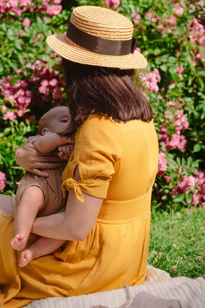 Çiçek açan bahçede Neşeli Anne ve Bebeğin Portresi