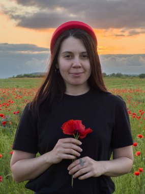 Haşhaş tarlasında kırmızı şapkalı genç kadın portresi