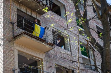 Ukrayna bayrağı, Kyiv 'in Sviatoshynskyi ilçesinde 24 Nisan 2025' te çıkan Rus roket yangınından zarar gören bir evin penceresinde, Kyiv 'in 04 / 24 / 2025' te bombalanmasının sonuçları.