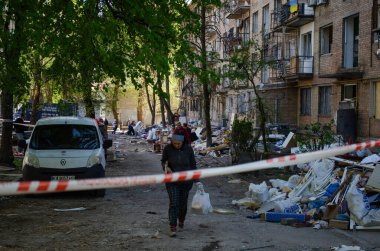 24 Nisan 2025 'te Kyiv' in Sviatoshynskyi ilçesinde, kırık camlı bir evden eşyalarını taşıyan bir kadın, Rus roketatarından zarar gördü..