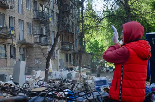 24 Nisan 2025 'te Kyiv' in Sviatoshynskyi ilçesinde Rus füze saldırısında hasar gören bir evin kalıntılarını temizleyen gönüllülerin işlerini genç bir adam yönetiyor..