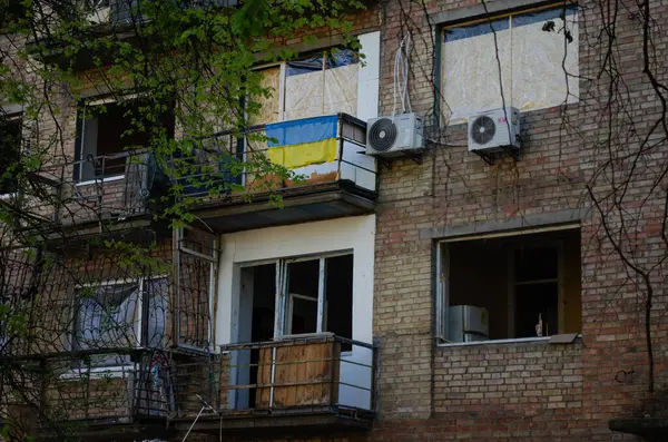 Ukrayna bayrağı, Kyiv 'in Sviatoshynskyi ilçesinde 24 Nisan 2025' te çıkan Rus roket yangınından zarar gören bir evin penceresinde, Kyiv 'in 04 / 24 / 2025' te bombalanmasının sonuçları.