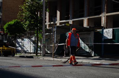 Kyiv, Ukrayna - 28 Ağustos 2025: Bir kamu işçisi Ukrayna başkentindeki bombardıman sonrasını temizlemek için çalıştıktan sonra elinde süpürgeyle Kyiv 'in ana caddesinde yürüyor