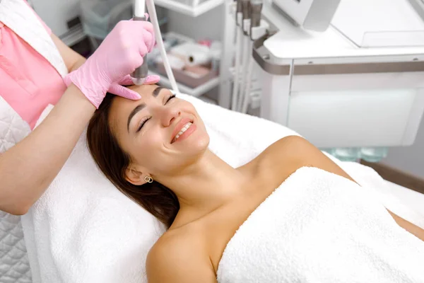 Rejuvenating therapy,Skin resurfacing, facial muscles of the client are lifted and toned using a microcurrent machine by the esthetician at the beauty salon. Cosmetology service