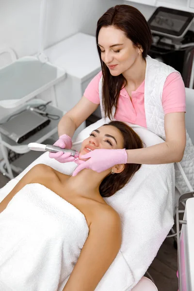 美容美发沙龙的美容师用微型电流机提升和调整患者的皮肤皮 护肤服务 面部肌肉 — 图库照片