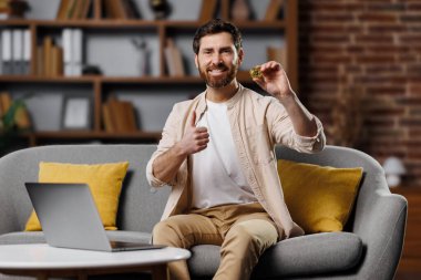 Sakallı bir adam şık bir oturma odasında rahat bir kanepede otururken elinde kurabiyeyle mutlu mesut oturuyor. Önündeki dizüstü bilgisayar rahatlatıcı bir mola verdiğini gösteriyor..