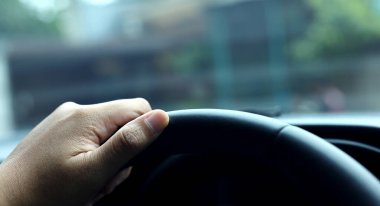 Close-up of a male hand on steering wheel. Right side of the wheel. Blurred background. clipart