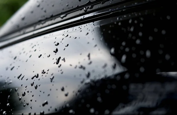 Siyah metalik araba gövdesine damlaların seçici odak noktası