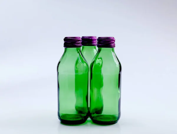 一套紫色瓶盖的绿色玻璃瓶 因白人背景而被隔离 — 图库照片