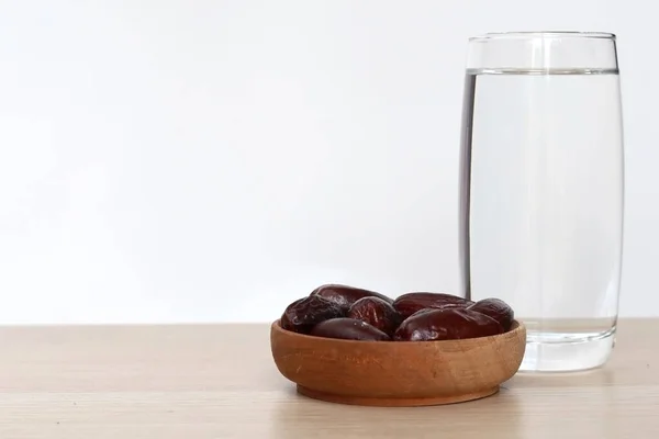 Ένα Ποτήρι Νερό Ένα Μπολ Χουρμάδες Φρούτων Ξύλινο Τραπέζι Και — Φωτογραφία Αρχείου