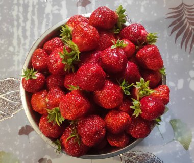 Masanın üzerinde bir kase çilek var..