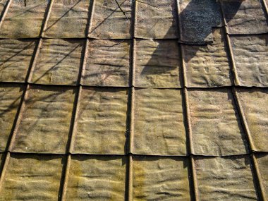 Eski evdeki metal çatı kiremitleri, çatıya yakın. Paslı demir bir yaprağın arka planı.