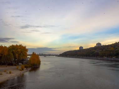 Dnipro Nehri manzarası ve şehir merkezindeki sarı ağaçlar. Tarihi mimari ve manzara, Kyiv 'in doğası. Sonbaharda Ukrayna 'nın başkenti Kyiv' de. Güzel gökyüzü.