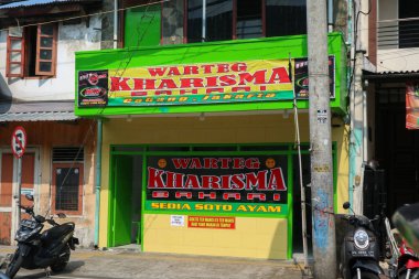 Yogyakarta, Endonezya - 20 Mart 2023: Parlak sarı ve yeşil imza renk şemasına sahip Warteg adı verilen geleneksel bir lokanta hizmete açıktır. Warteg Kharisma Bahari Bhayangkara caddesinde
