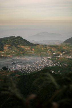 Dieng Platosu 'nun şehirli ve tepelerle çevrili havadan görüntüsü. Prau dağından görüldü.