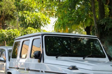 Park alanında beyaz bir Mercedes Benz G-Sınıfı AMG 63. Arabanın dış detayları..