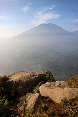 Arkasında dağ olan bir uçurum. Kaya kayalığı dağ taşının bir parçası. Boş uzay uçurumunun kenarında bulutların üzerinde mavi gökyüzü.