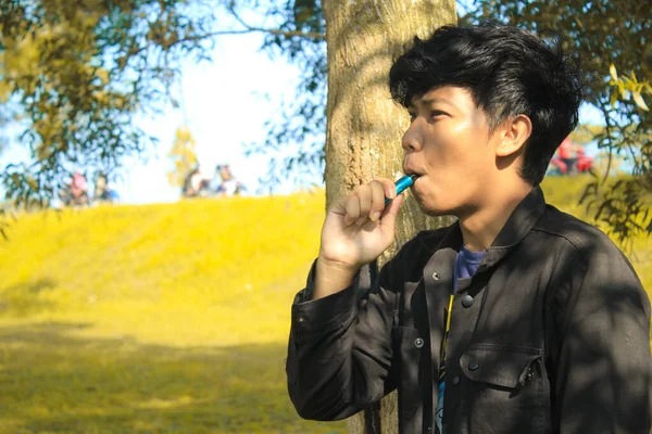 Avkopplande Ung Asiatisk Man Bär Svart Jacka Inhalera Blå Vape — Stockfoto