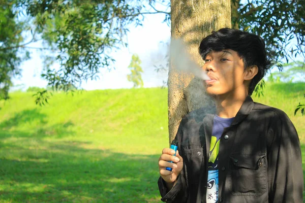 Pria Asia Muda Yang Santai Meniup Sistem Pod Vape Menghasilkan — Stok Foto