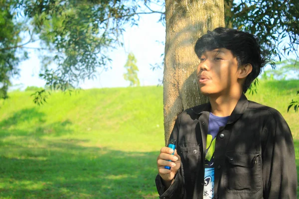Расслабленный Молодой Азиат Дует Стручок Системы Вырабатывает Облако Туман Деревьями — стоковое фото