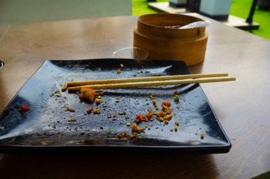 Siyah kirli tabak ve bambu çubuğu bambu yemek kabıyla ahşap masaya istiflenmiş.