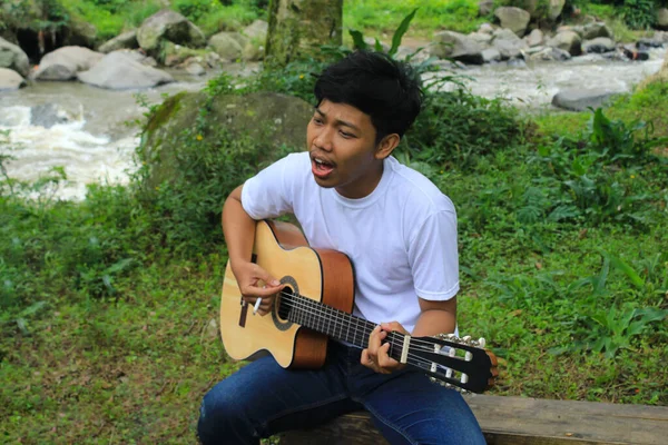 Glücklicher Junger Asiatischer Mann Spielt Akustikgitarre Und Singt Flussufer Wenn — Stockfoto