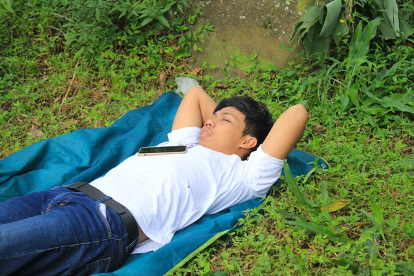 young man asian is lying on the lawn and daydreaming, relaxing and thinking