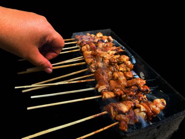 Geleneksel baharat ve otlarla ızgara yerinde satay tavuğu beyaz arka planda izole edilmiş lezzetli görünüyor.