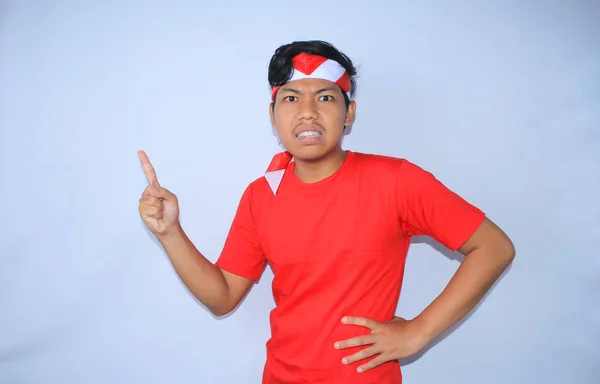 怒っているインドネシアの若者は インドネシア独立記念日に赤いTシャツとヘッドバンドを着て彼のフォーフィンガーを指摘 — ストック写真