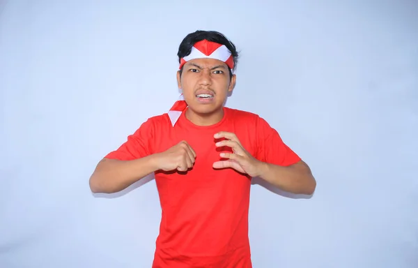 怒っているインドネシアの若者は インドネシア独立記念日に赤いTシャツとヘッドバンドを着て手を打つために手を挙げた — ストック写真